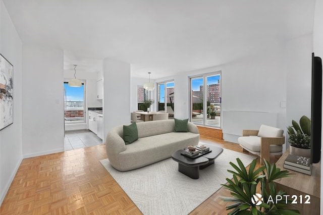 living area featuring a healthy amount of sunlight, a city view, and baseboards