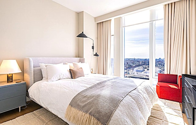 bedroom with a view of city and wood finished floors