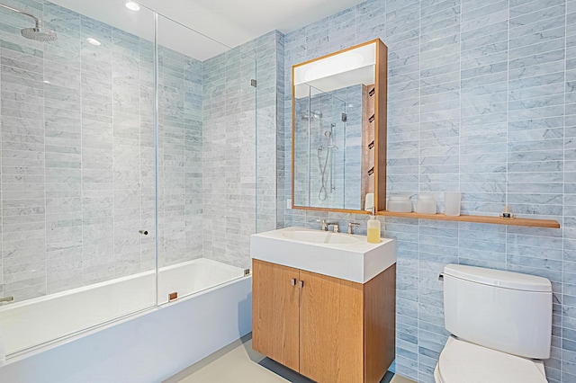 full bathroom featuring toilet, shower / bath combination with glass door, vanity, and tile walls