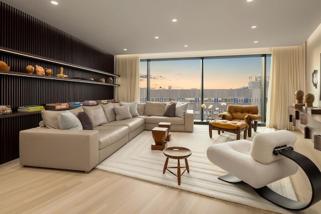 living room with light wood-style floors, recessed lighting, and a wall of windows