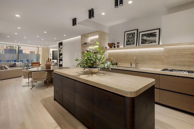 kitchen with open floor plan, a sink, light countertops, stainless steel gas cooktop, and backsplash