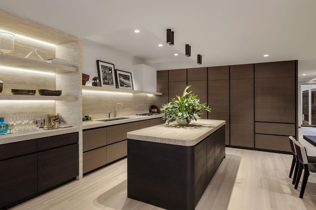 kitchen featuring a kitchen island, light countertops, a sink, and dark brown cabinetry