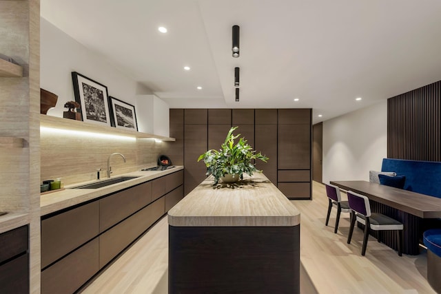 kitchen with light countertops, a kitchen island, modern cabinets, and a sink