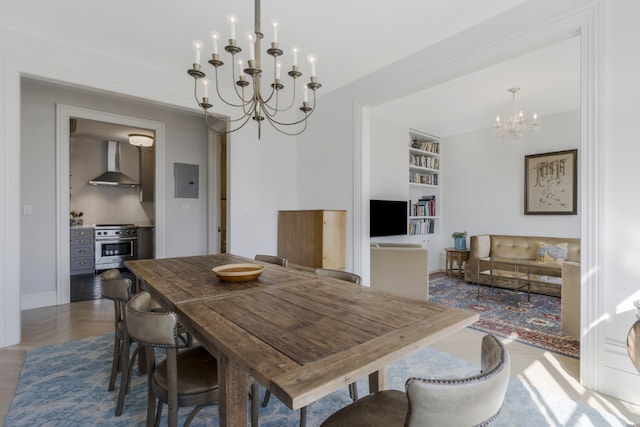 dining area with an inviting chandelier, electric panel, and built in features