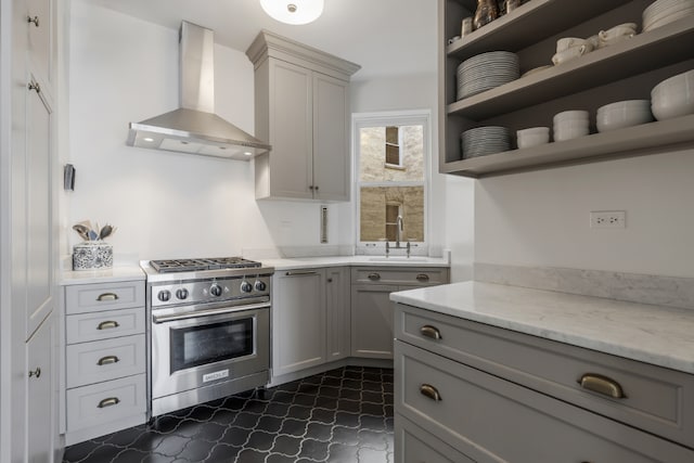 kitchen featuring sink, gray cabinetry, stainless steel stove, light stone countertops, and wall chimney range hood