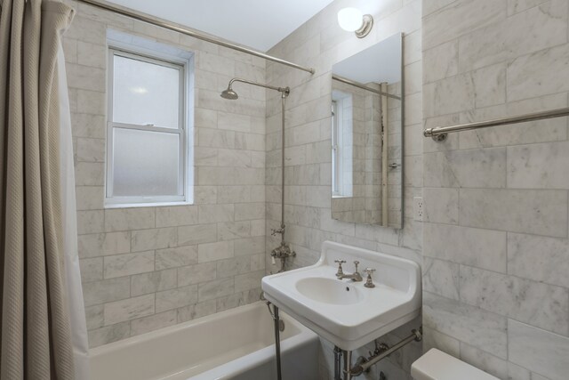 full bathroom with shower / bathtub combination with curtain, sink, tile walls, and toilet