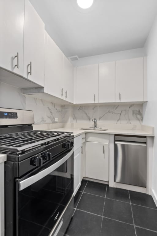 kitchen with tasteful backsplash, stainless steel dishwasher, gas stove, and white cabinets