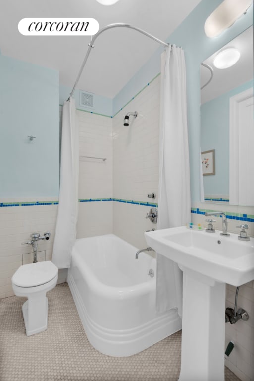 bathroom featuring tile walls, tile patterned flooring, toilet, and shower / tub combo with curtain