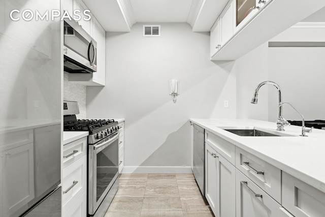 kitchen with a sink, stainless steel appliances, light countertops, baseboards, and visible vents