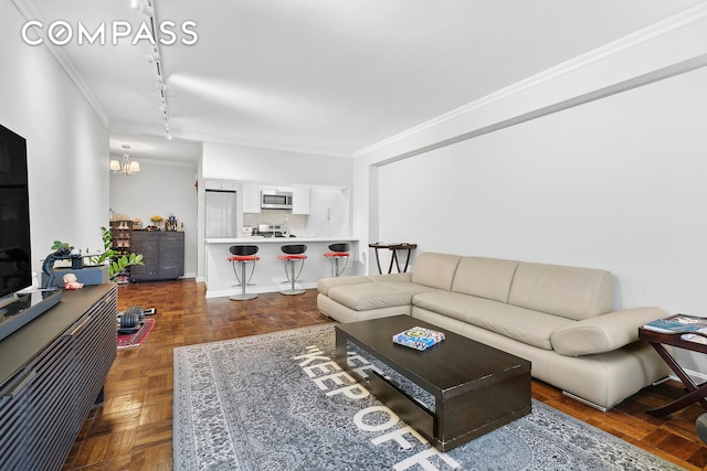 living room featuring an inviting chandelier, crown molding, baseboards, and track lighting