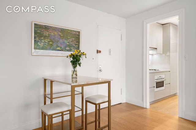 dining space with light wood-type flooring and baseboards