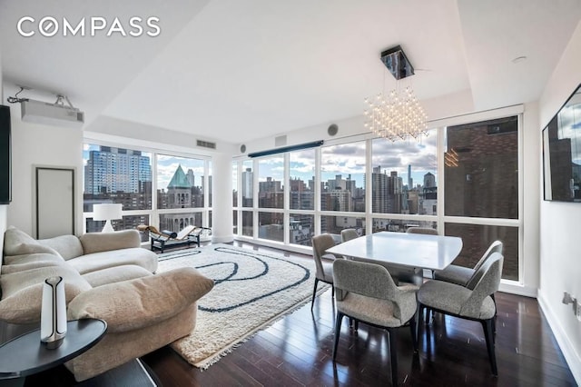 living room with an inviting chandelier, a city view, baseboards, and hardwood / wood-style flooring