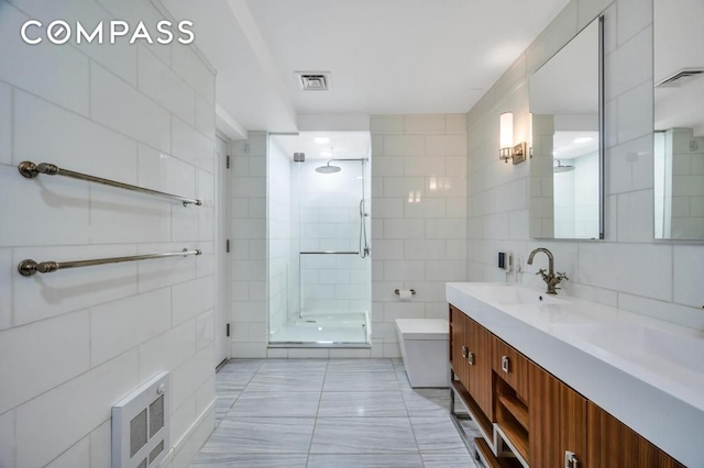 bathroom with visible vents, a stall shower, tile walls, and a sink