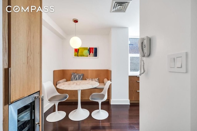 dining room with dark hardwood / wood-style floors, beverage cooler, and breakfast area