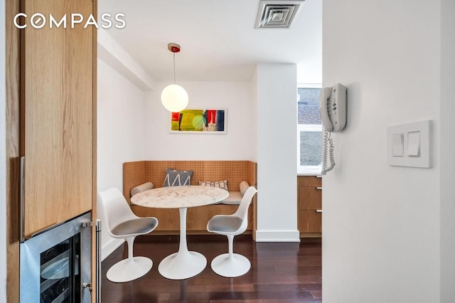 dining space featuring breakfast area, baseboards, wine cooler, visible vents, and dark wood-style floors