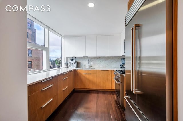 kitchen featuring dark wood-type flooring, high quality appliances, modern cabinets, and light countertops