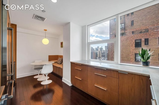 bar featuring visible vents, a view of city, decorative light fixtures, baseboards, and dark wood-style flooring