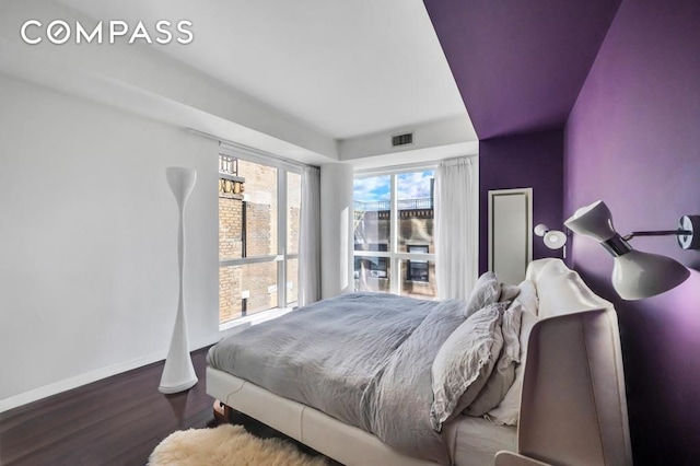 bedroom with wood finished floors, visible vents, and baseboards