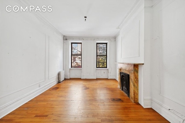 unfurnished living room with radiator, crown molding, and light hardwood / wood-style flooring