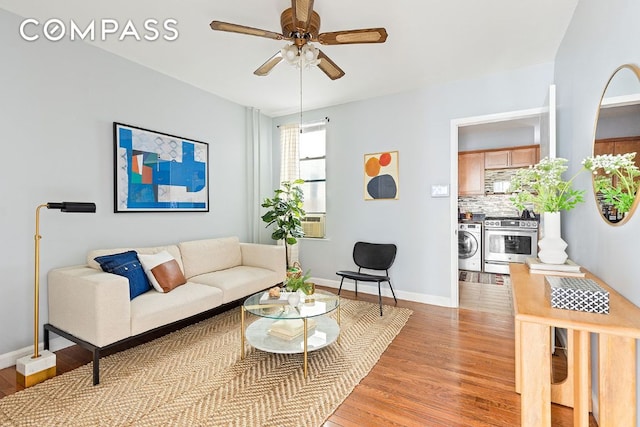 living room featuring washing machine and dryer, cooling unit, ceiling fan, and light hardwood / wood-style flooring