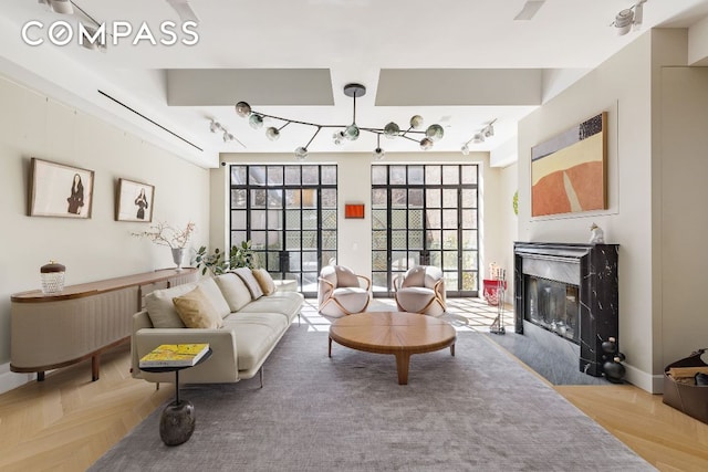 living room featuring a premium fireplace, rail lighting, and light parquet flooring