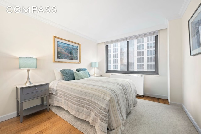 bedroom featuring radiator heating unit, light hardwood / wood-style flooring, and ornamental molding