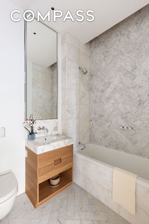 bathroom with toilet, tiled shower / bath combo, and vanity