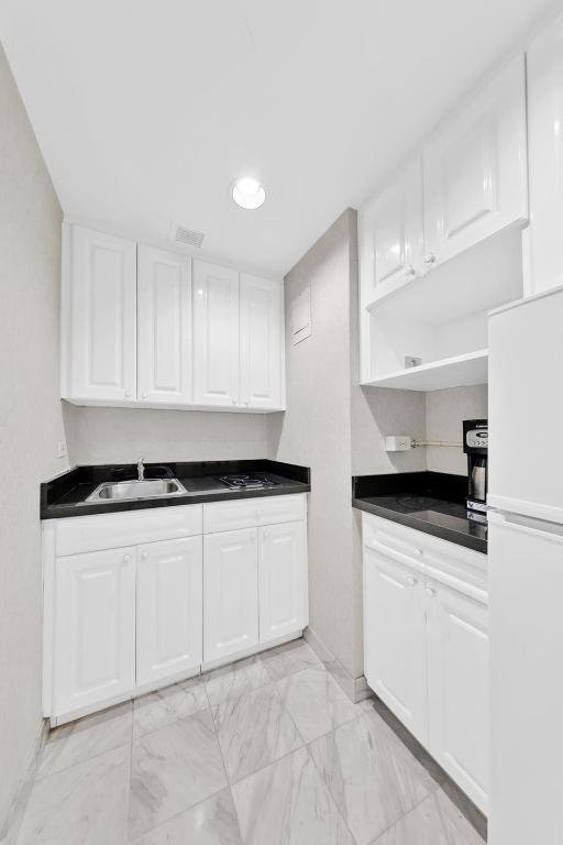 kitchen with white refrigerator, sink, and white cabinets