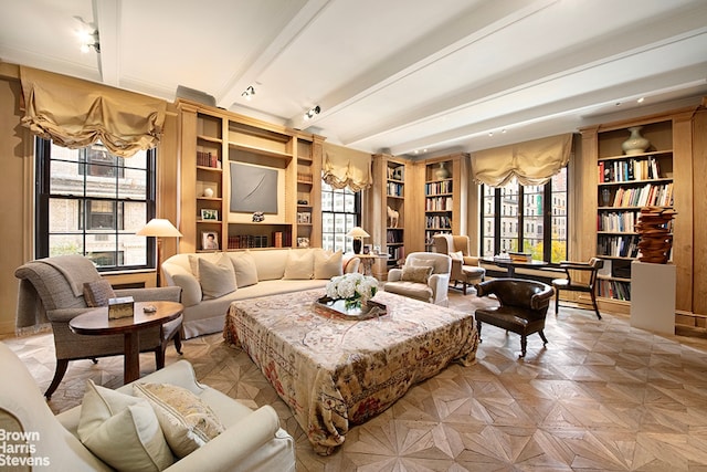 sitting room featuring beam ceiling, light parquet flooring, built in shelves, and a healthy amount of sunlight