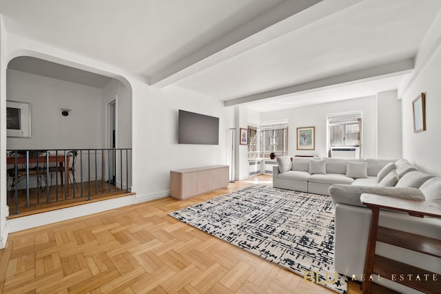 living area with baseboards, arched walkways, and beam ceiling