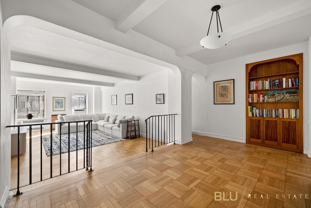 interior space with arched walkways, beamed ceiling, built in features, and baseboards