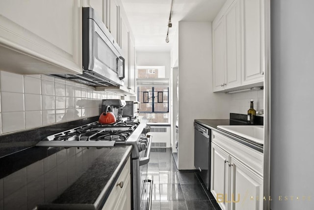 kitchen with sink, appliances with stainless steel finishes, white cabinetry, backsplash, and radiator heating unit