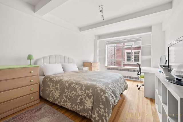 bedroom featuring hardwood / wood-style flooring, radiator, built in desk, and beam ceiling