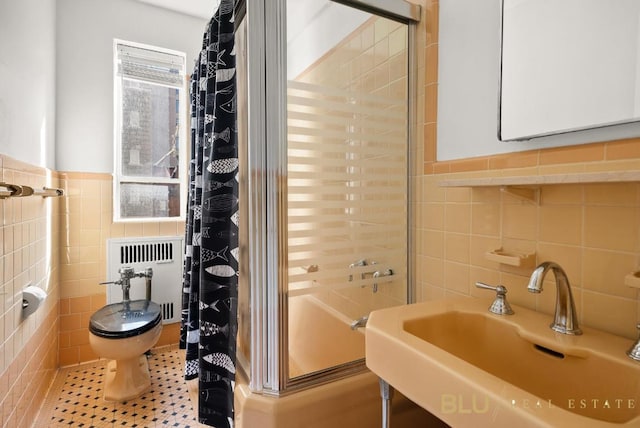 full bathroom featuring sink, enclosed tub / shower combo, tile walls, radiator heating unit, and toilet