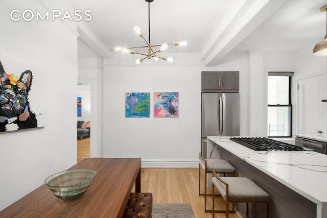 kitchen featuring light hardwood / wood-style flooring, stainless steel refrigerator, dark brown cabinets, light stone counters, and decorative light fixtures