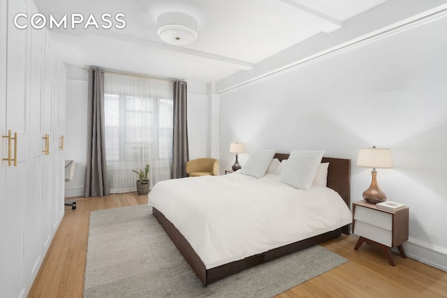 bedroom featuring beamed ceiling and light hardwood / wood-style flooring