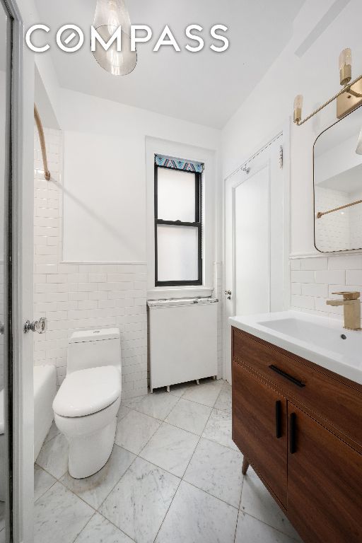 bathroom with tile walls, vanity, and toilet