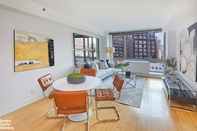 dining area with a view of city, baseboards, and wood finished floors