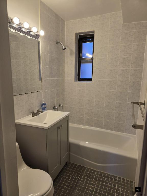 bathroom featuring tile walls, toilet, washtub / shower combination, vanity, and tile patterned floors