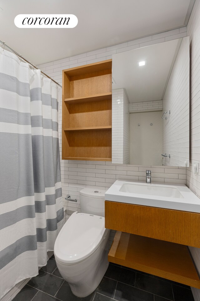 12 W 72nd St Unit 3Kl, New York City, NY 10023 - bathroom featuring tile patterned flooring, toilet, vanity, tile walls, and tasteful backsplash