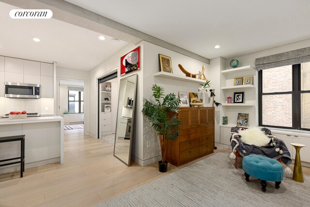 12 W 72nd St Unit 3Kl, New York City, NY 10023 - kitchen with stainless steel microwave, white cabinetry, light wood-style flooring, light countertops, and recessed lighting