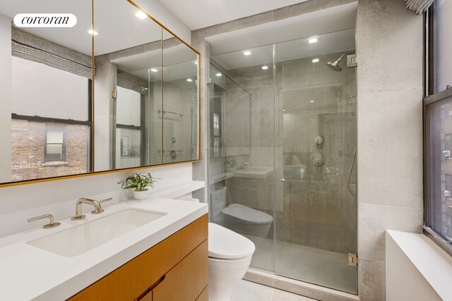 12 W 72nd St Unit 3Kl, New York City, NY 10023 - bathroom featuring toilet, vanity, a shower stall, tile patterned floors, and tile walls