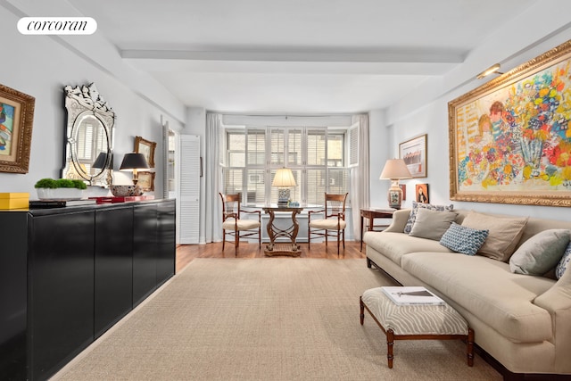 living area with beam ceiling, visible vents, and wood finished floors