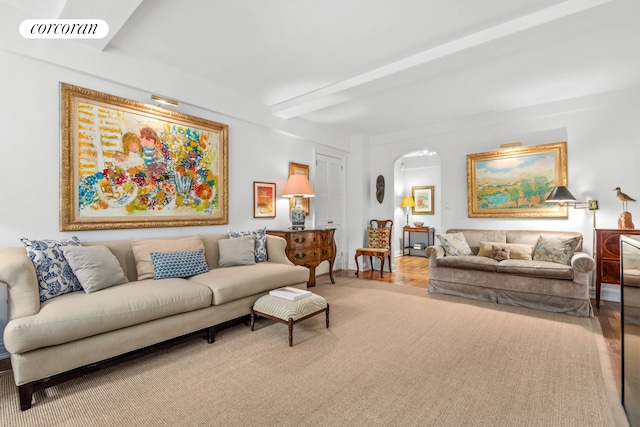 living room featuring visible vents, arched walkways, and beam ceiling