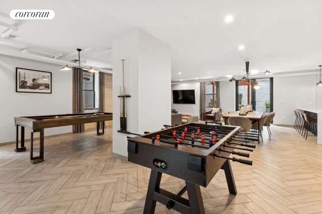 rec room with an inviting chandelier and light parquet flooring