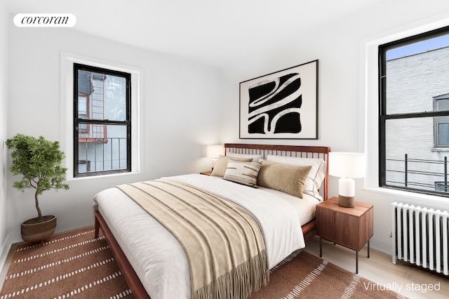 bedroom with multiple windows, hardwood / wood-style flooring, and radiator