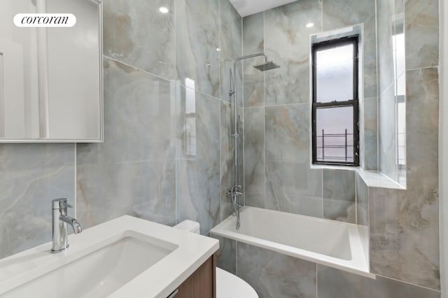 full bathroom featuring tile walls, toilet, vanity, and tiled shower / bath combo