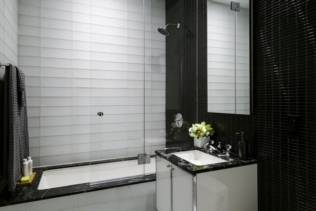 full bathroom featuring vanity, tiled shower / bath combo, and tile walls