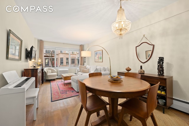 dining area featuring a chandelier, a baseboard radiator, and light wood-style flooring