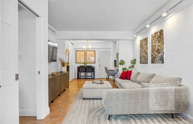 living room with rail lighting, a notable chandelier, and baseboards